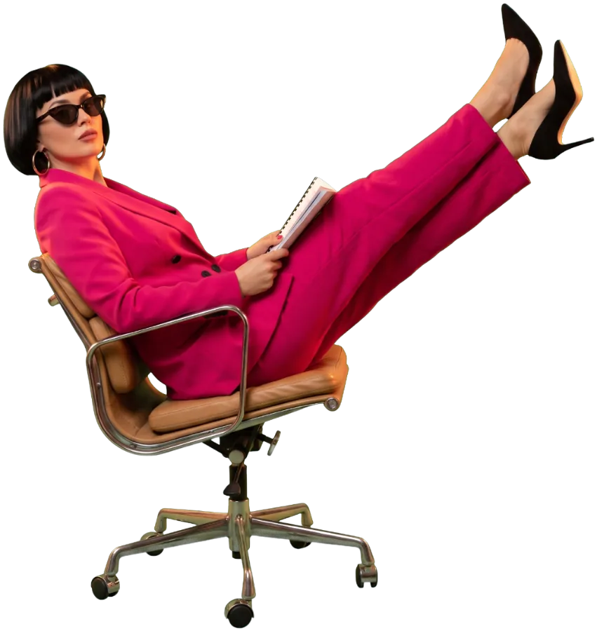 A woman in a pink suit leans back in an office chair with her feet up, reading a report