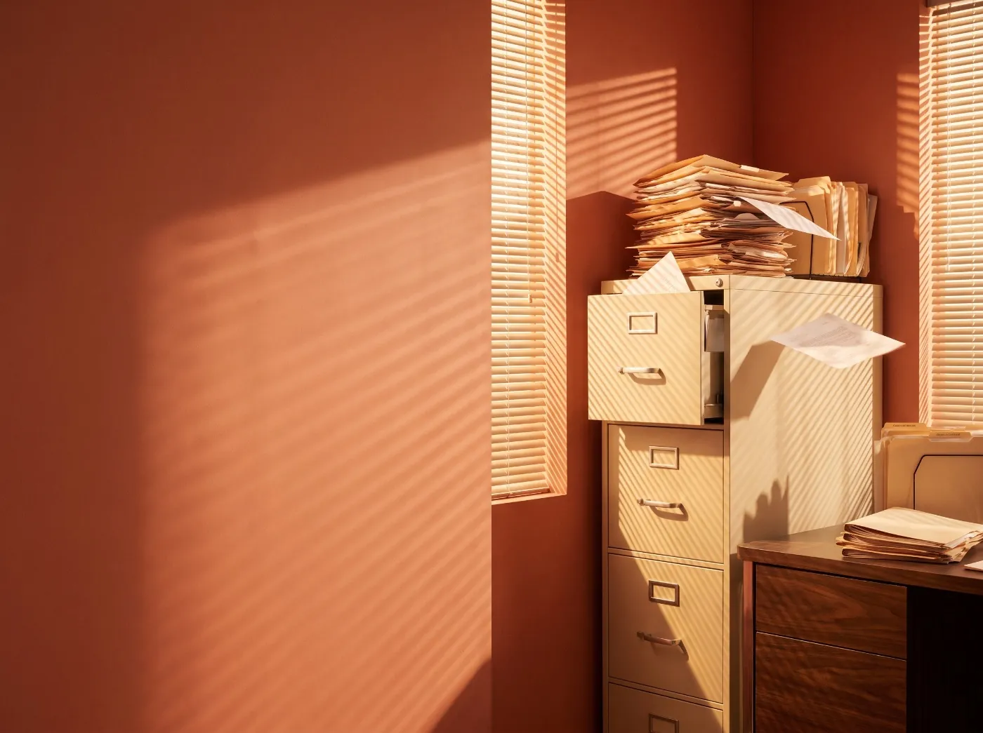 A sunlit office corner with a filing cabinet overflowing with paper files